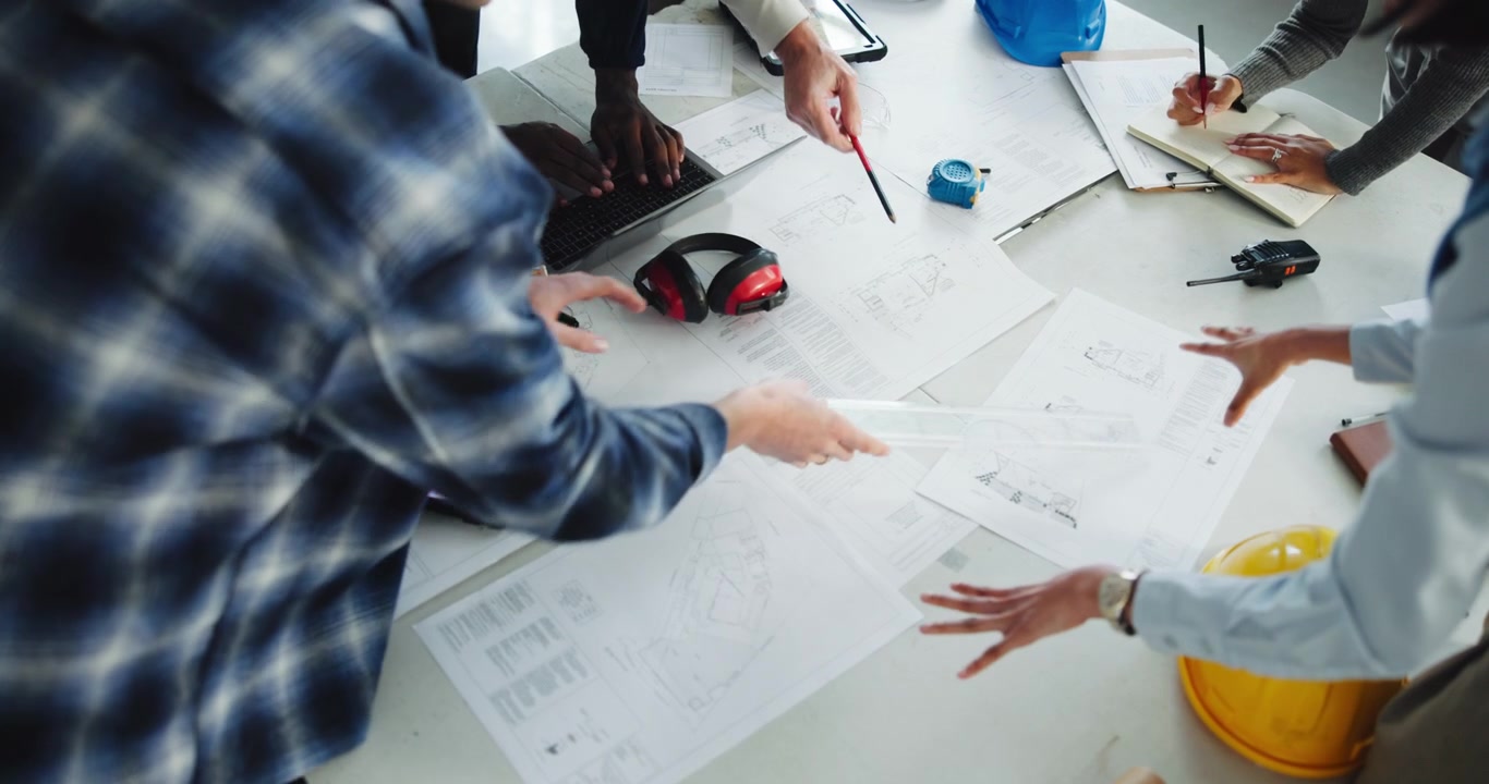Diverse Team of Architects Collaborating on Construction Blueprints