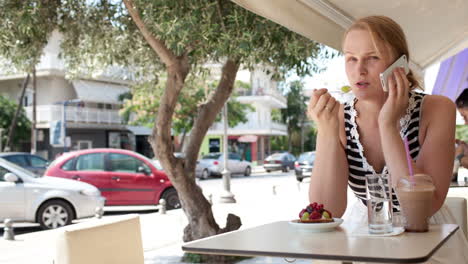 Woman-sitting-at-a-cafeteria-talking-on-a-mobile