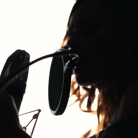 young woman recording a song in a professional recording studio. female vocal. black and white.
