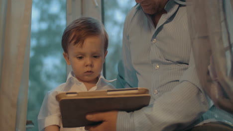 father and little son using tablet computer at home