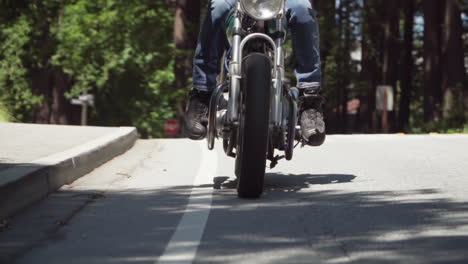 slow motion of motorcyclist with leather jacket coming to a stop on a wooded road