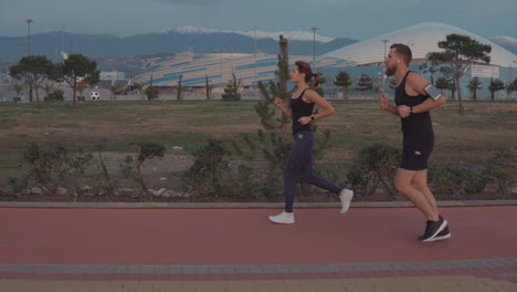 pareja corriendo en el parque con un estadio en el fondo