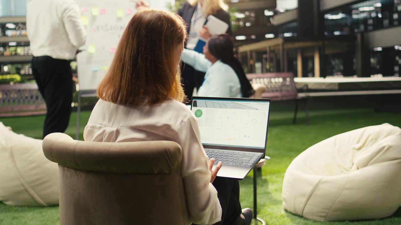 Businesswoman Working on Laptop During Team Meeting in Modern Office