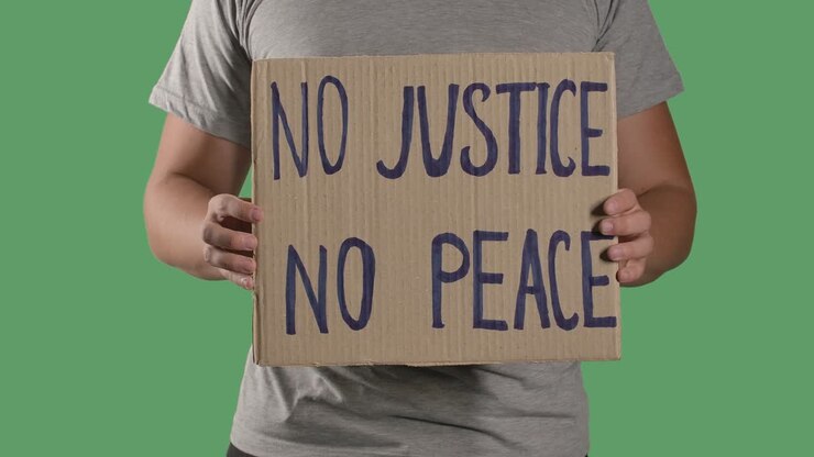 Man holds in front of him a poster from a cardboard box with the words NO JUSTICE NO PEACE. Concept of strike and anti racism. Isolated a green screen, chroma key. Close up. Slow motion