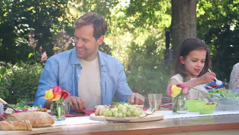 three generation white family having lunch in the garden