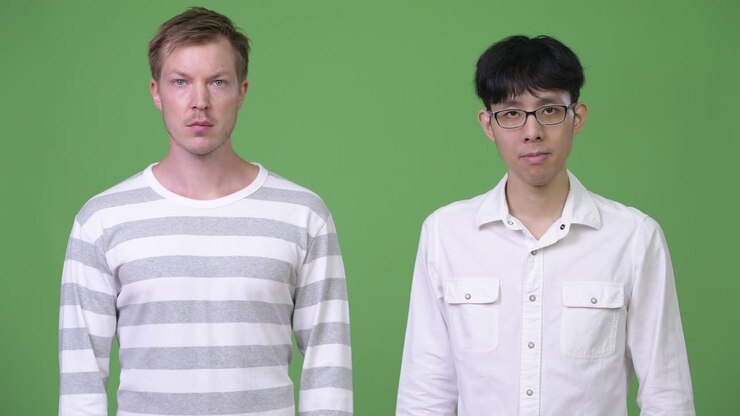 Two young multi-ethnic businessmen together against green background