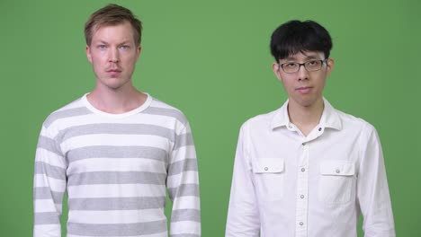 두 명의 젊은 다민족 사업가들이 녹색 배경에 함께합니다.