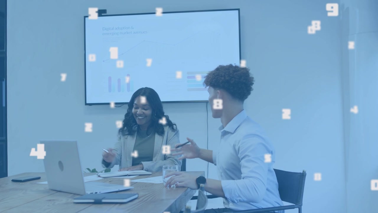Woman tapping laptop while man reviewing docs, causing numeric overlay on charts in office meeting