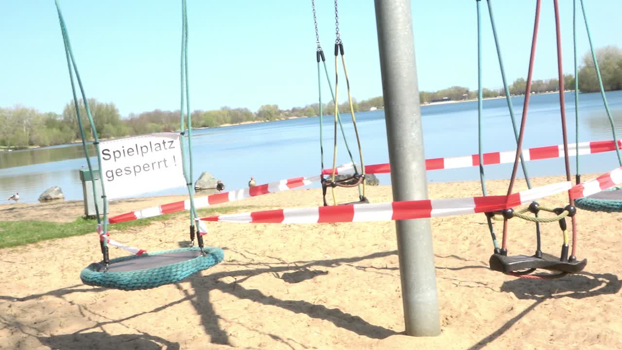 закрытая детская карусель на берегу озера для отдыха, знак с немецкой надписью: игровая площадка закрыта