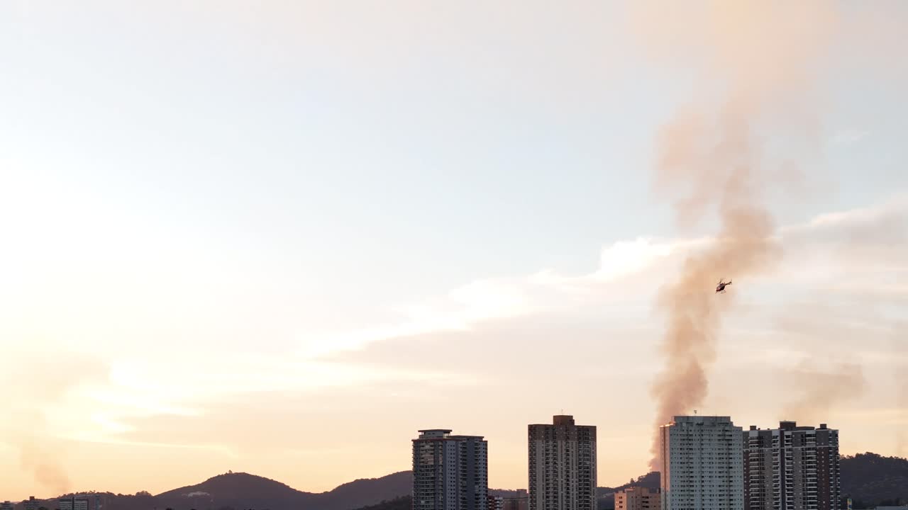 Helicopter over City During Sunset with Smoke Plume