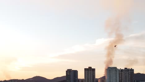 helicopter over city during sunset with smoke plume