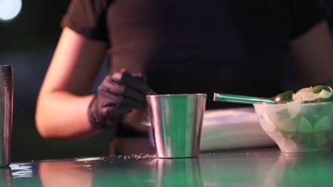 a woman prepares cocktail recipe with sugar and lemon in a metal container