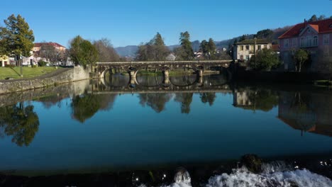 old bridge crossing river vez in town of arcos de valdevez in portugal reflects perfectly in calm water