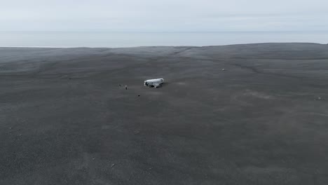 los turistas visitan el accidente del avión douglas super dc-3 en la playa negra en solheimasandur, islandia