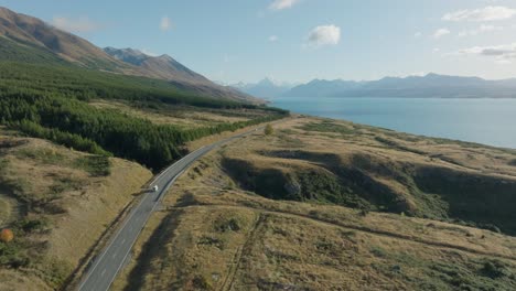 Majestuosa-Vista-Aérea-De-Drones-De-Una-Autocaravana-Conduciendo-A-Través-Del-Parque-Nacional-Aoraki-Mount-Cook-Con-Paisajes-Alpinos-Montañosos-En-La-Isla-Sur-De-Nueva-Zelanda-Aotearoa