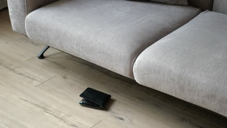 wallet on the floor near a grey sofa