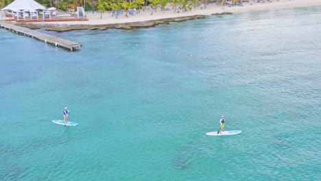 tourists paddle sup on caribbean sea of dominicus beach, dominican republic