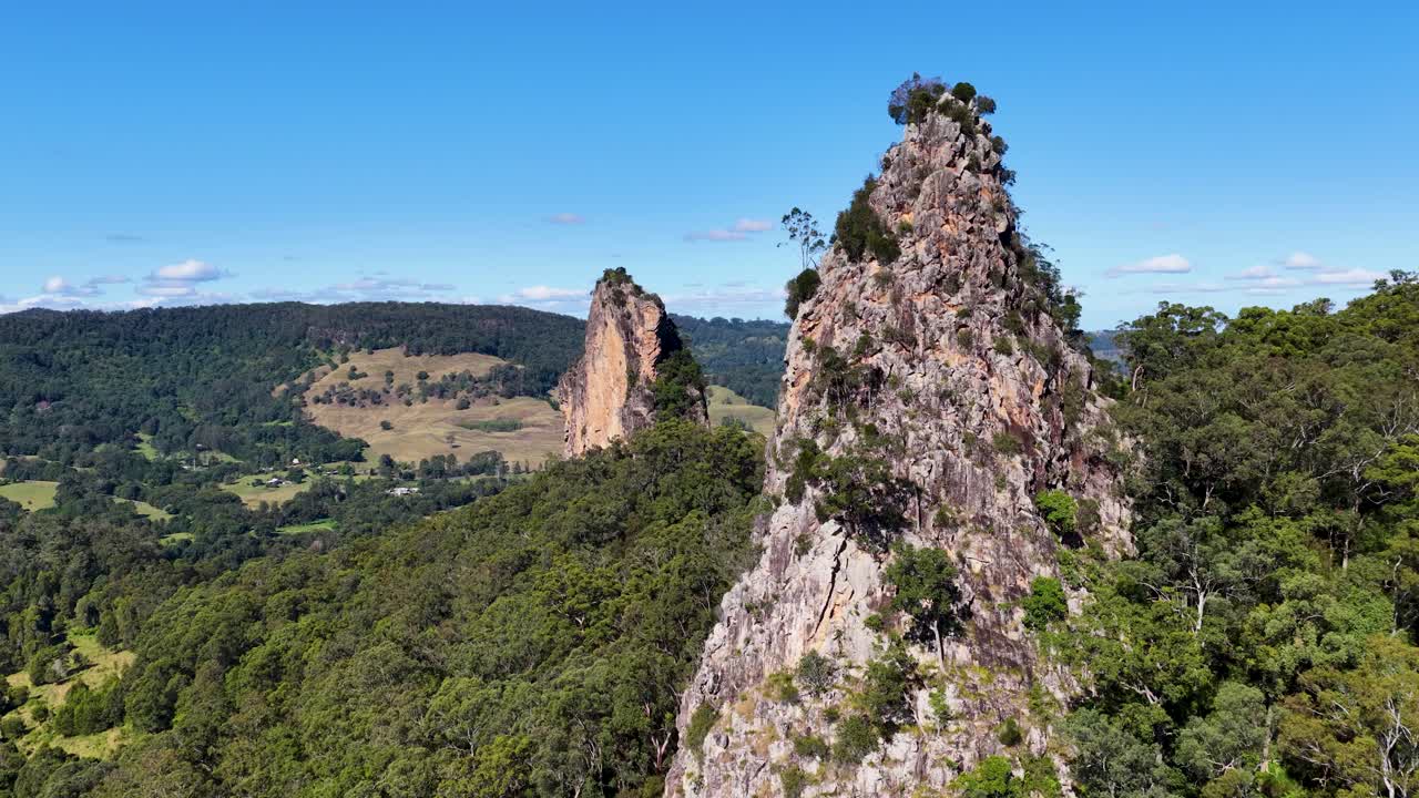 Aerial footage of Nimbin Rocks, showcasing lush greenery and striking rock formations under clear blue skies