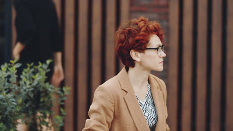 businesswoman sitting on bench outdoors and using laptop