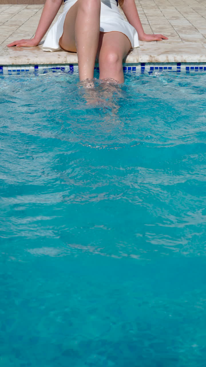 Donna con gonna bianca e pedicure rossa che sguazza in una piscina. Verticale