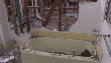 Tilt-down-from-the-exposed-beams-of-a-wall-to-a-bathtub-inside-a-home-in-the-process-of-being-demolished