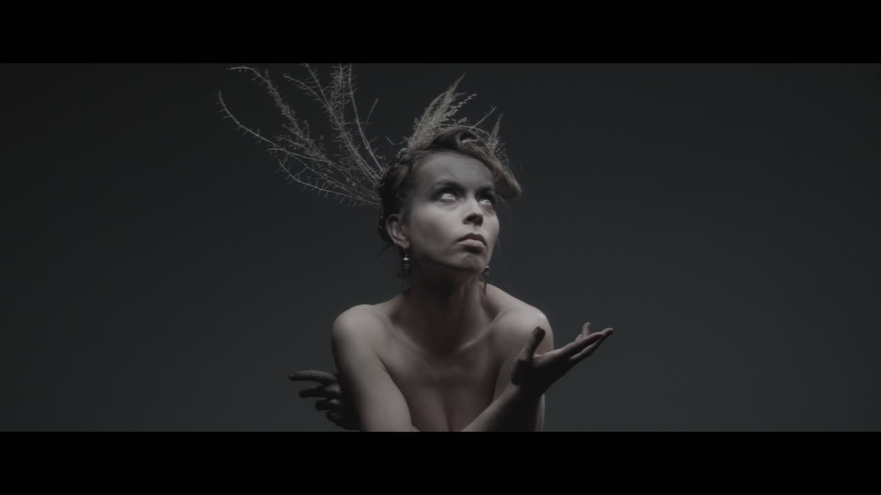 Uma mulher vestida como mãe natureza move-se lentamente em um movimento de dança