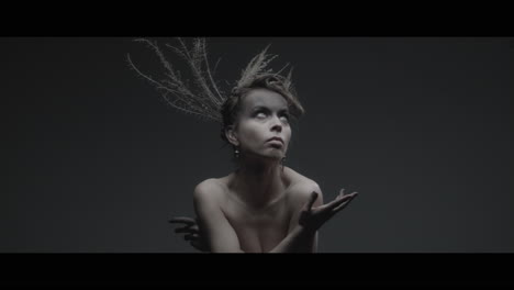 a woman dressed as mother nature moves slowly in a dance-like motion