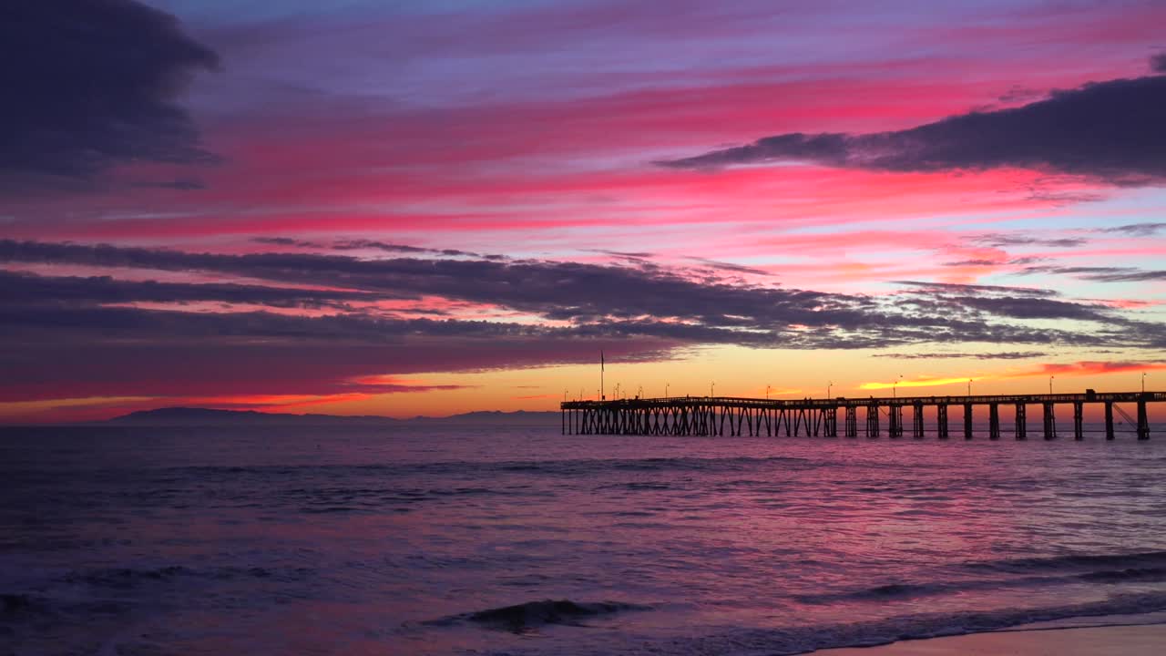 una hermosa costa roja anaranjada al atardecer tomada a lo largo de la costa central de california con el muelle de ventura distante 3