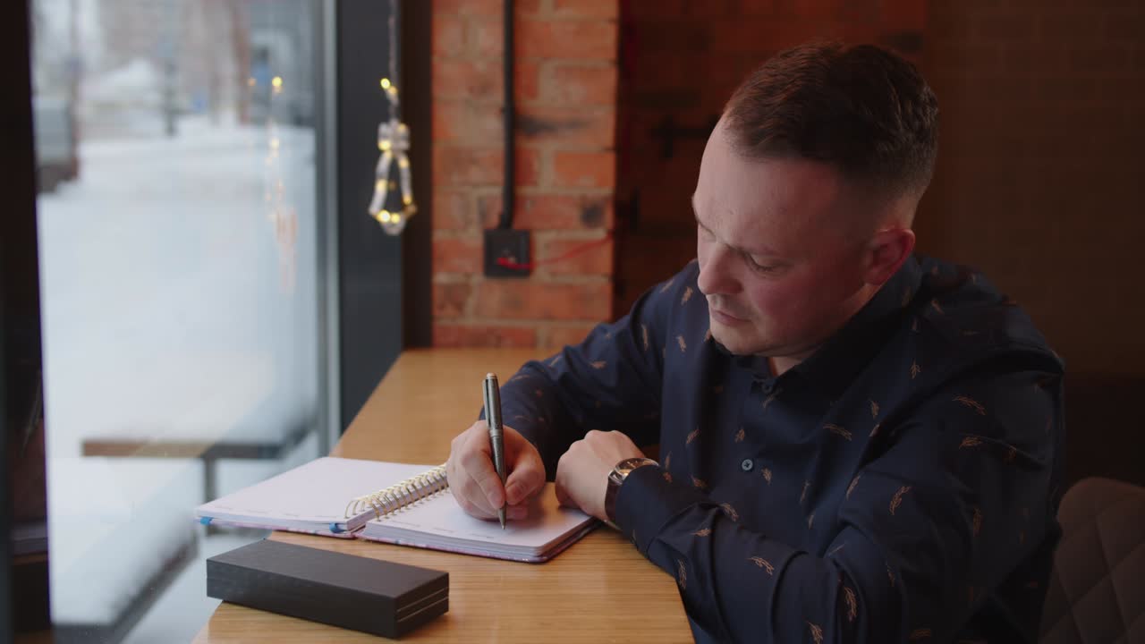 The man writes down in a notebook plans for the future. Man writes text notebook