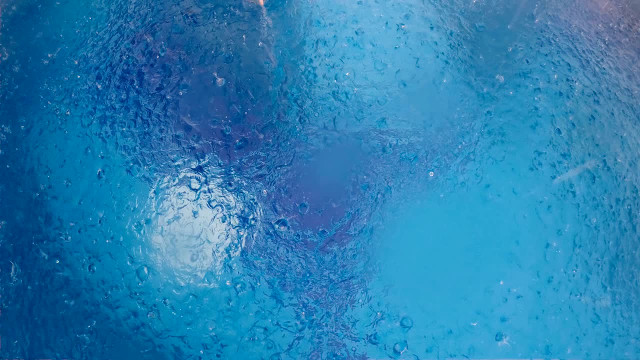 수영장 물 표면에 많은 비가 내리고, 공중에서 느린 동작으로 볼 수 있습니다.