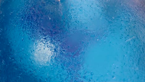 fuerte lluvia en la superficie del agua de la piscina, vista aérea en cámara lenta