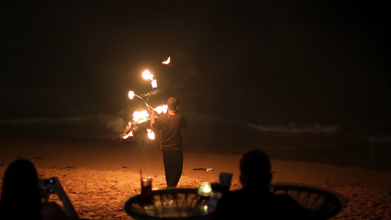 el intérprete hace girar el fuego en una playa nocturna