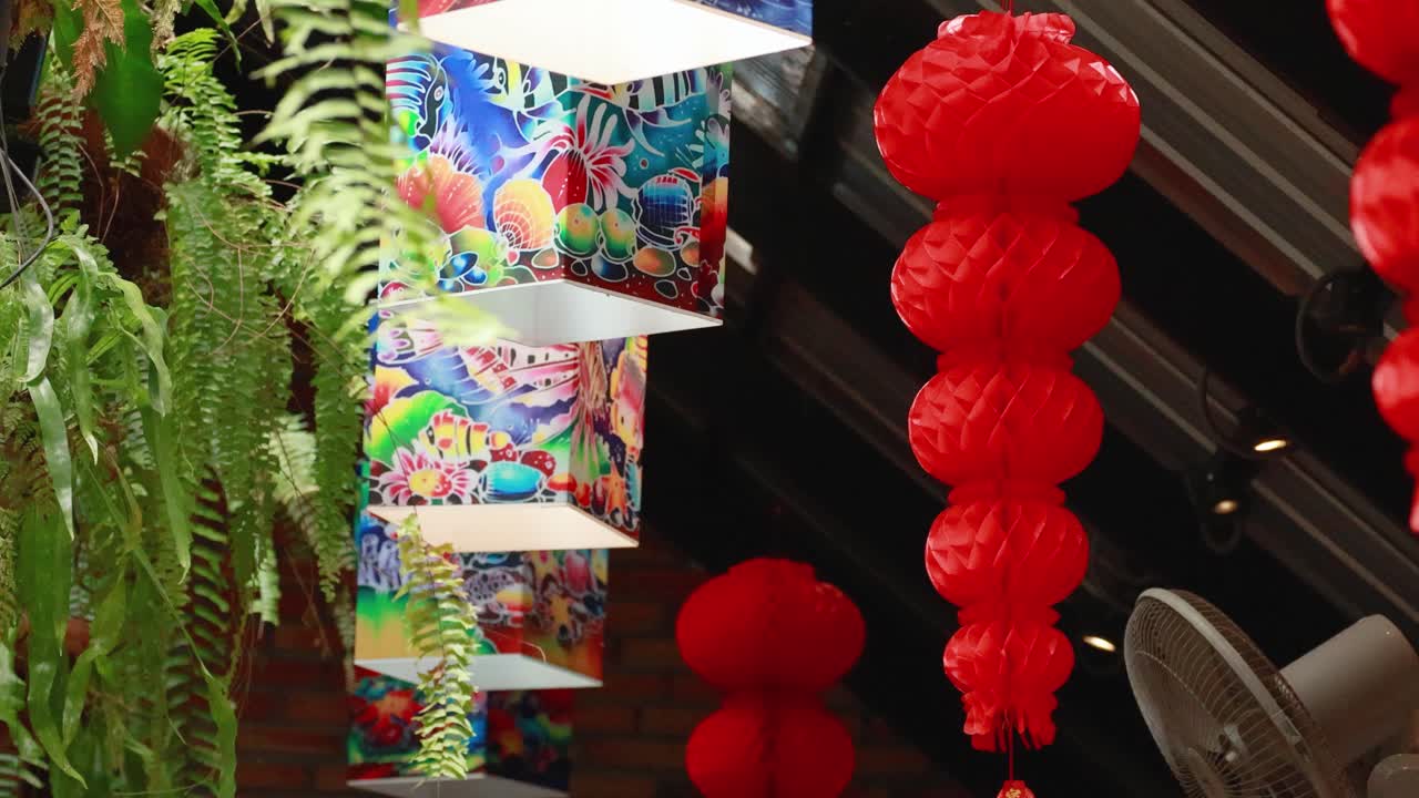 Colorful lanterns and lush greenery create a lively atmosphere in a Phuket market, captured with dynamic camera movement