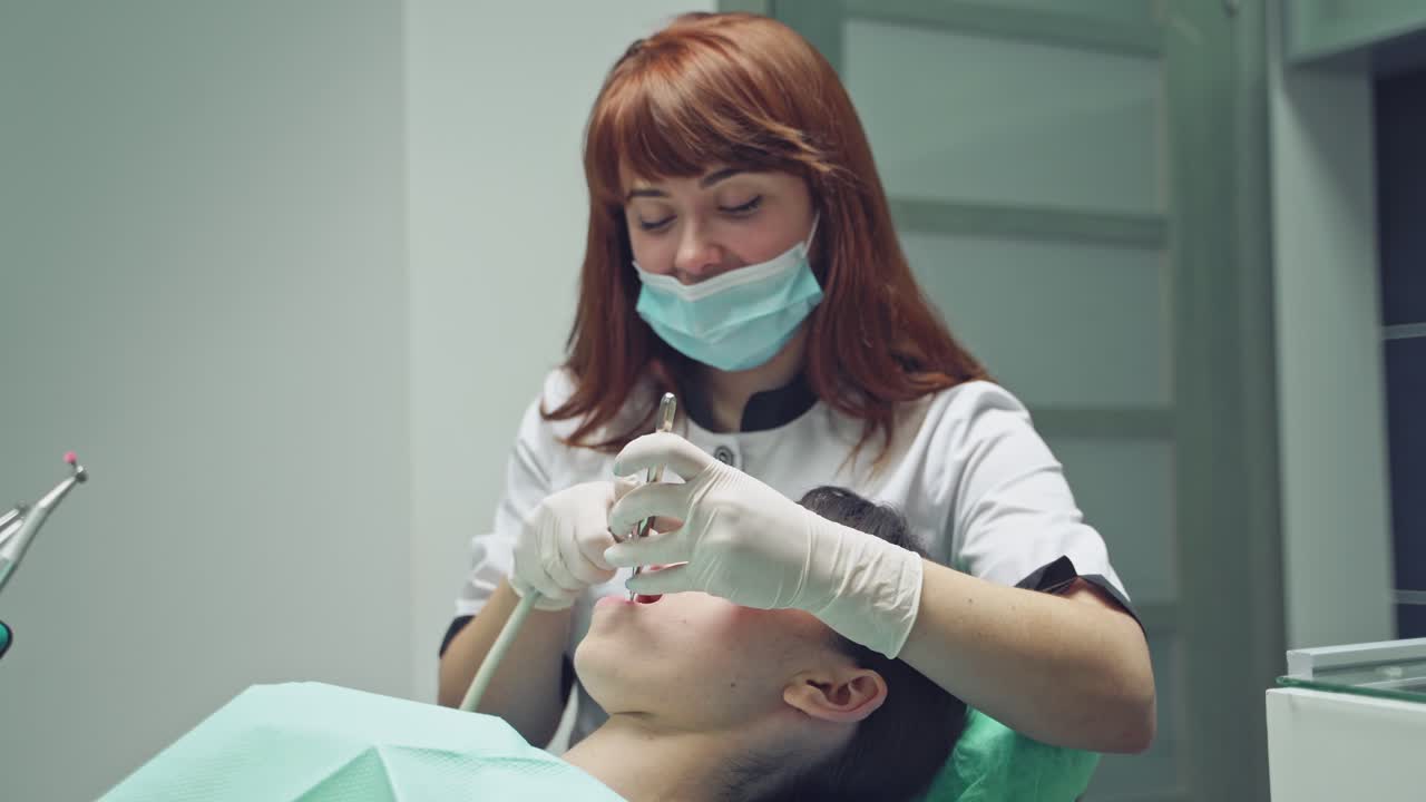 Young Female patient with open mouth examining dental inspection at dentist office. Dental clinic.