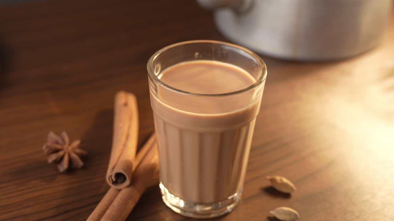 Chai indiano servito in tazze di vetro, preparato in una teiera di metallo con masala aromatici