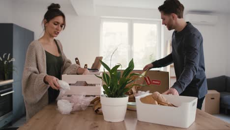 caucasian couple unpacking some kitchen stuff in new house.