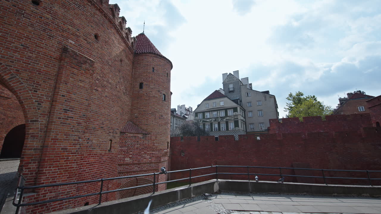 Historic brick towers of Barbakan Warsaw under a cloudy spring sky