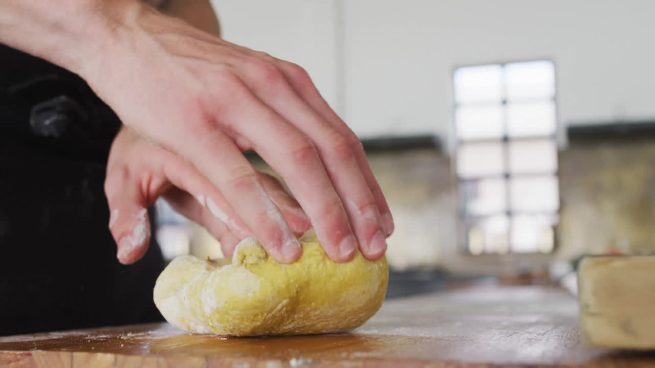 백인 남성 요리사 가 주방 테이블 에 반죽 을  ⁇ 고 있다