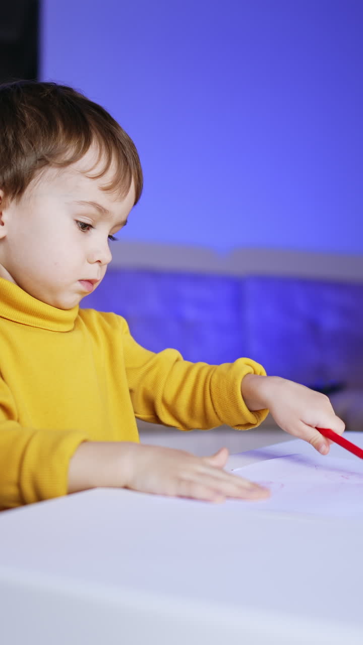 Small lovely kid drawing at the desk at home. Approaching the cute child focused