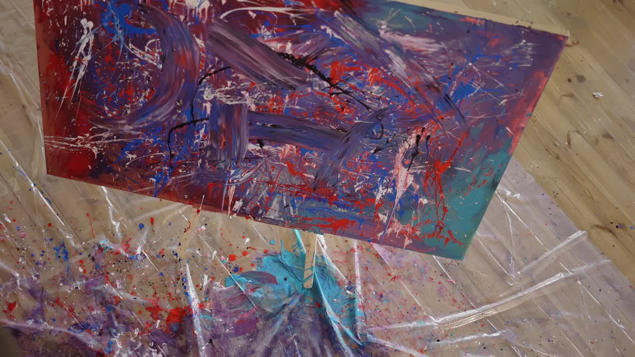 mujer pinta en un lienzo sumergiendo las manos en un frasco de pinturas, imágenes desde arriba