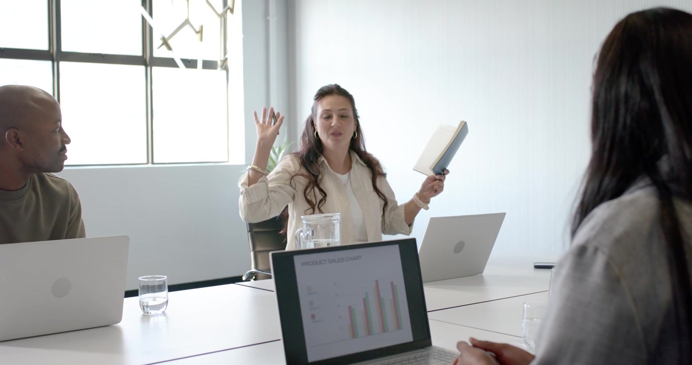 Diverse coworkers watching White woman presenting after seeing laptop bar chart in conference room