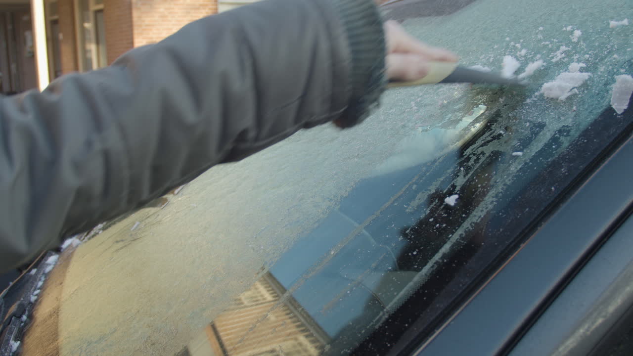 rascar el hielo de la ventana del coche en una soleada mañana de invierno