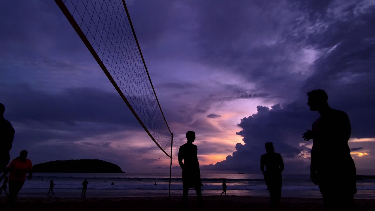 해가 지는 해변에서 배구 선수들이