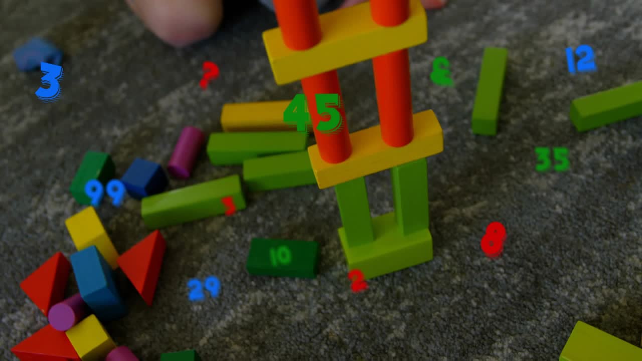 Child kneeling reaching and placing block, raising tower with numeric labels on blocks for learning