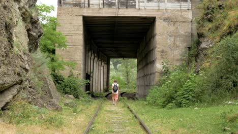 young girl walks on the reailway in the tunnel