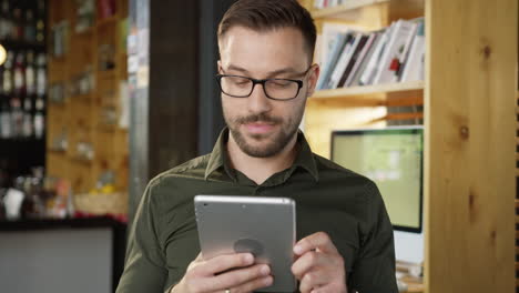 man using tablet in coffee shop working