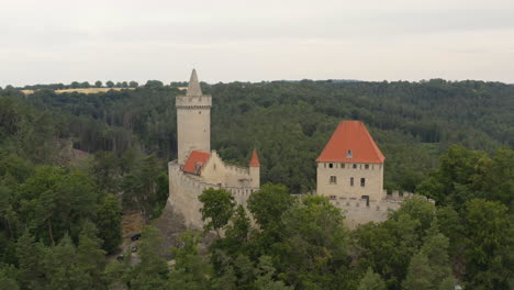 medieval kokorin castle in czechia on hilltop above forest landscape