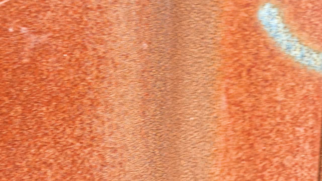 Close-up video of a rusted metal wall in Dunkirk, France, with faint graffiti marks. Static camera, natural daylight, textured orange-brown surface