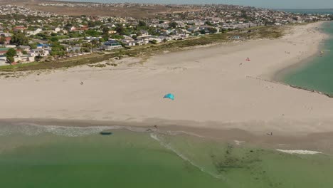 Kitesurfer-jumping-near-the-beach-at-Langebaan,-drone-shot