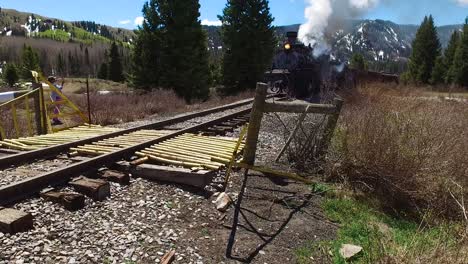 low angle rise up of cumbres and toltec steam train moving through colorado mounatins near chama new mexico